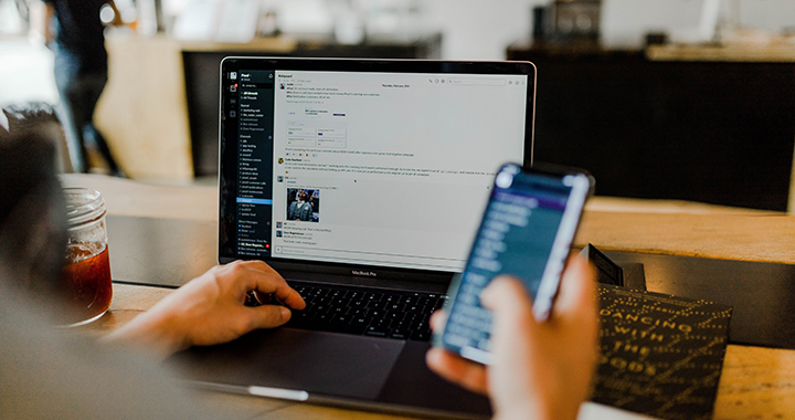 Person multitasking on laptop and phone